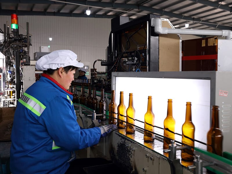 Light-panel inspection of amber glass bottles at the Shandong factory