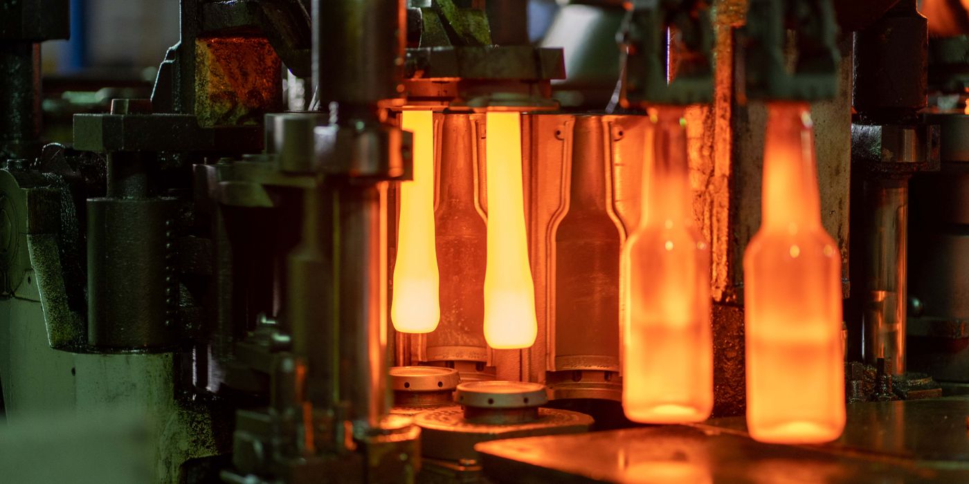 Glühend heiße Glasflaschen verlassen die Vorformen einer IS-Maschine