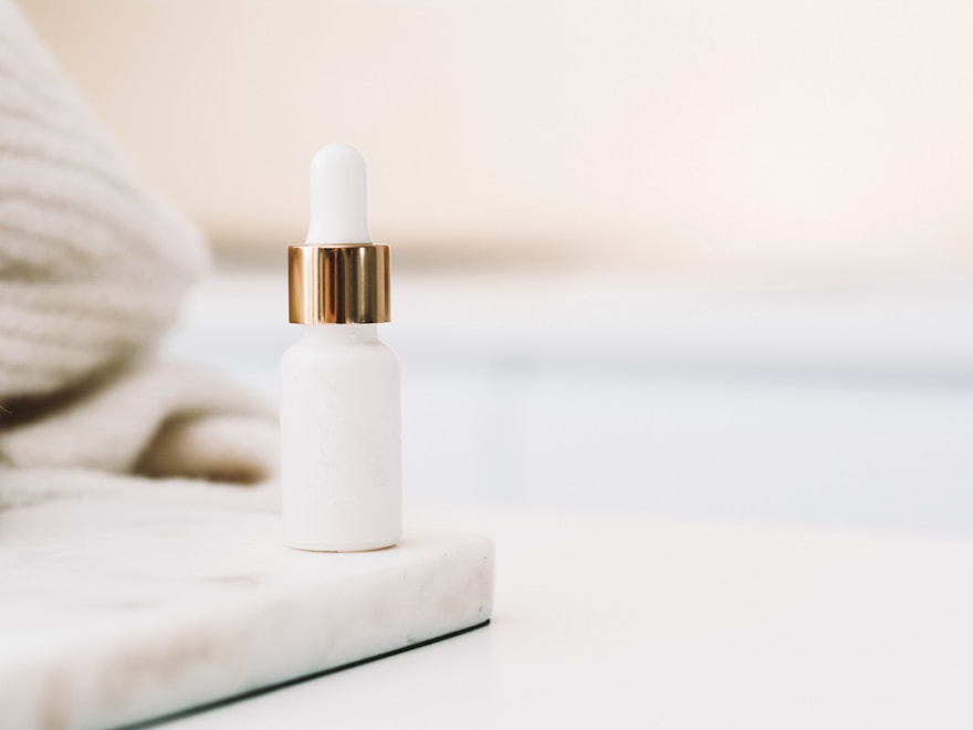 Frosted glass dropper bottle on a marble tile