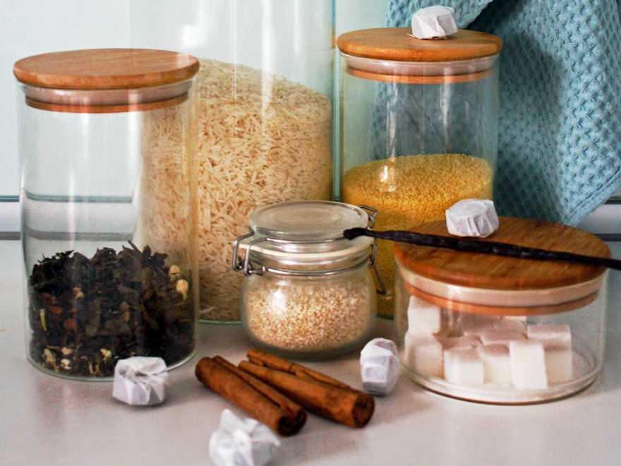 Glass kitchen storage jars with wooden lids on a counter