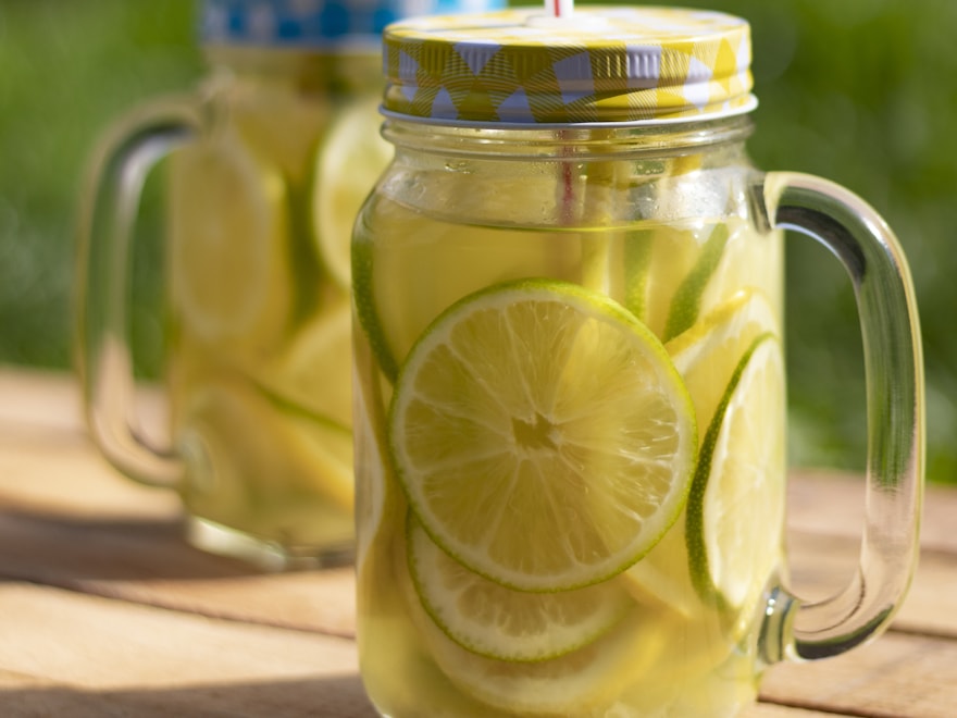Two handled glass mason jar mugs on a warm wooden surface