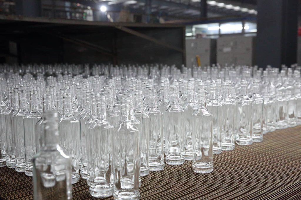 Reihen leerer Glasflaschen auf dem Kaltend-Transportband in der Glashütte von SGSBOTTLE