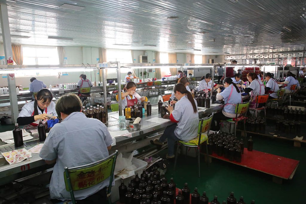Inspectors checking glass bottles at cold-end benches in an SGSBOTTLE factory