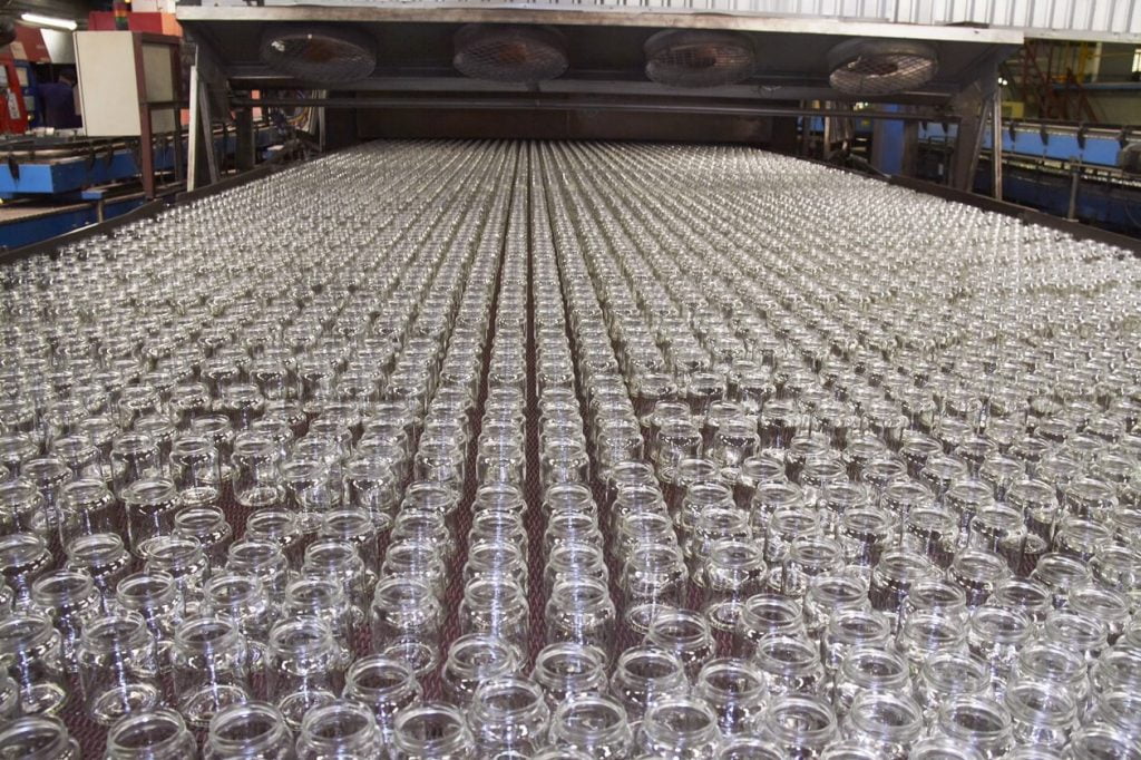 Rows of empty glass bottles moving along the cold-end conveyor after the annealing lehr