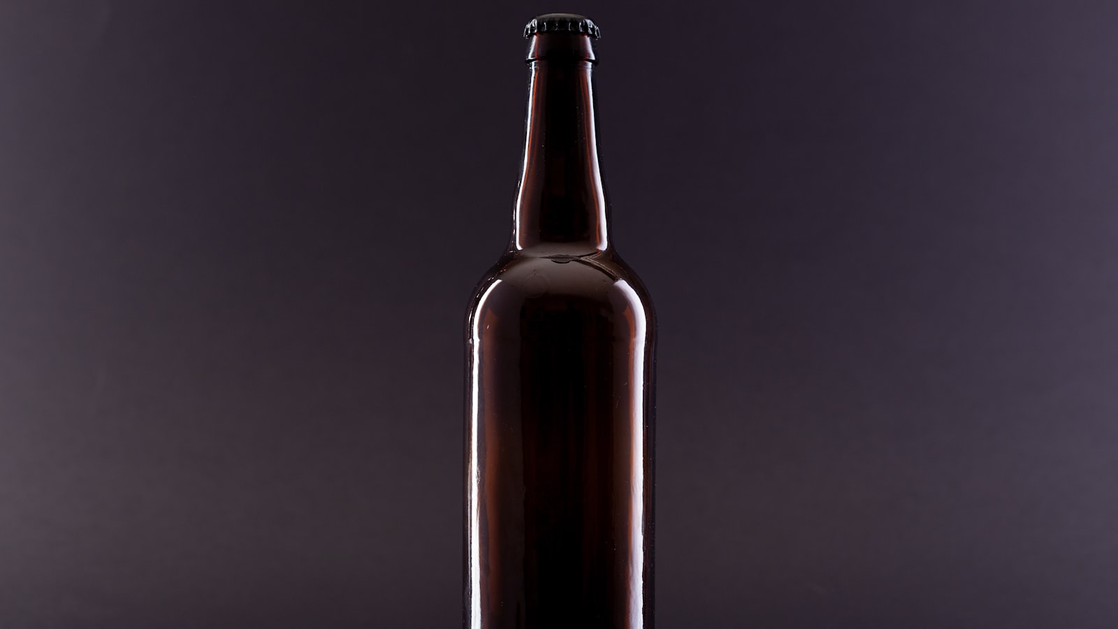 An amber glass beer bottle photographed against a dark background