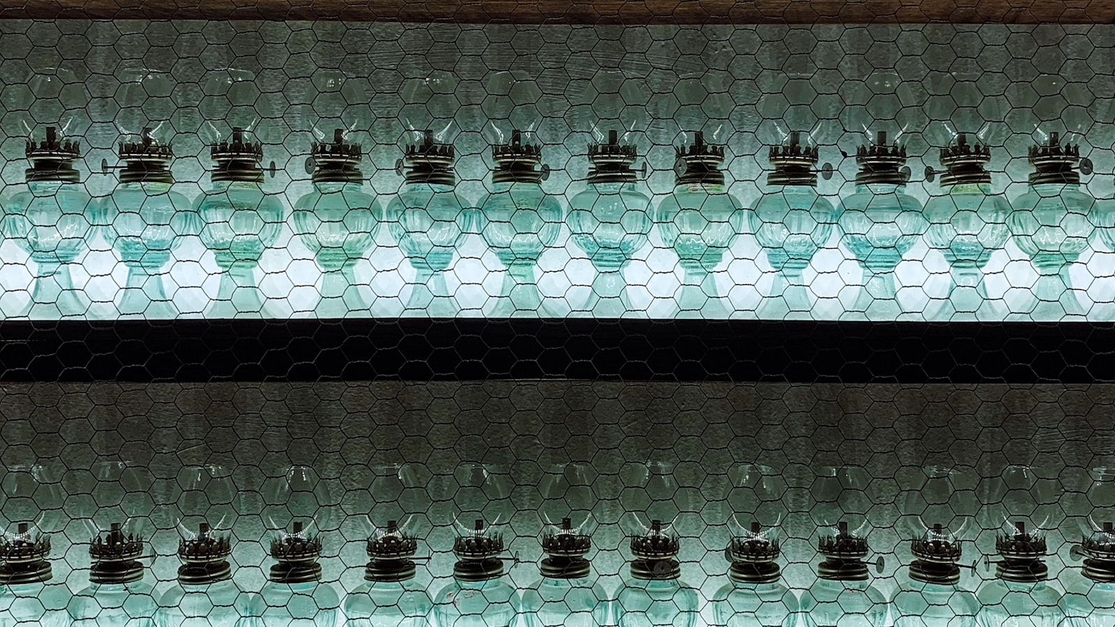 A row of glass bottles passing through cold-end inspection