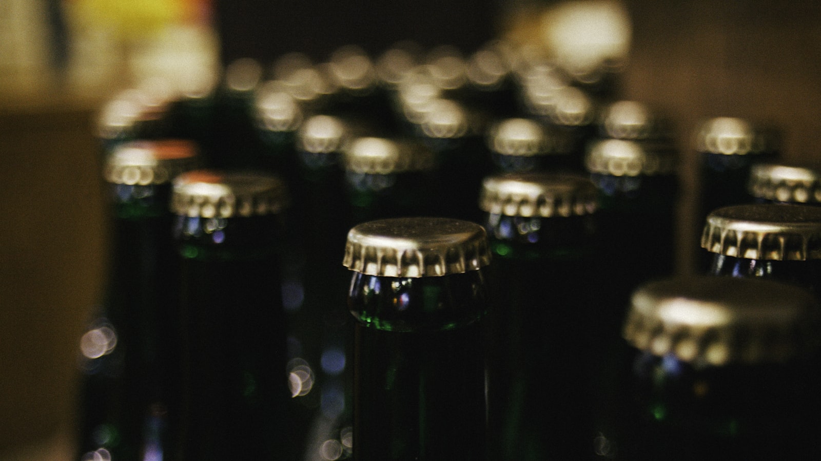 Rows of green glass bottles closed with gold crown caps
