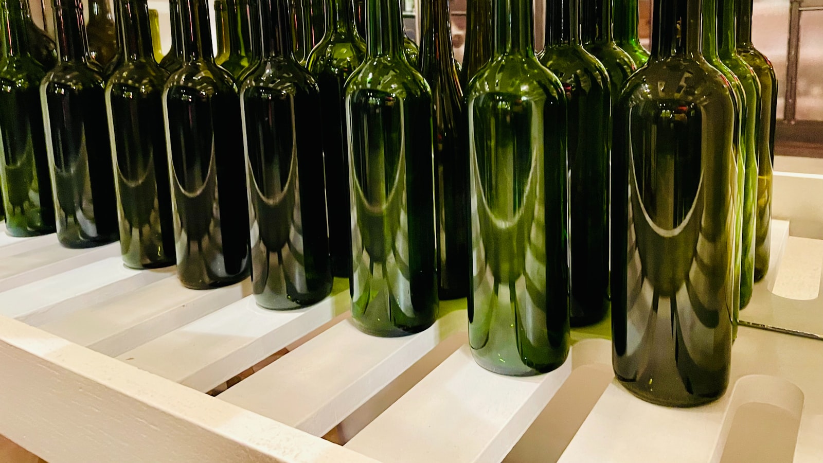 Green glass wine bottles resting in a metal rack