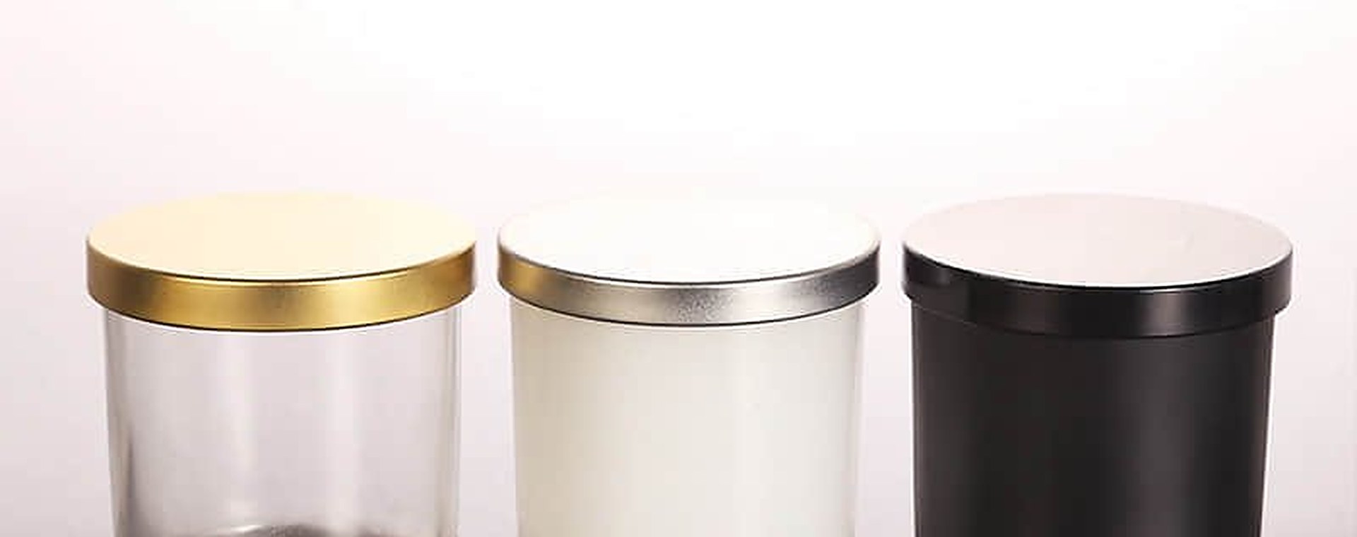 Drei Tumbler-Kerzengläser in Klar, Weiß und Schwarz mit Metalldeckeln