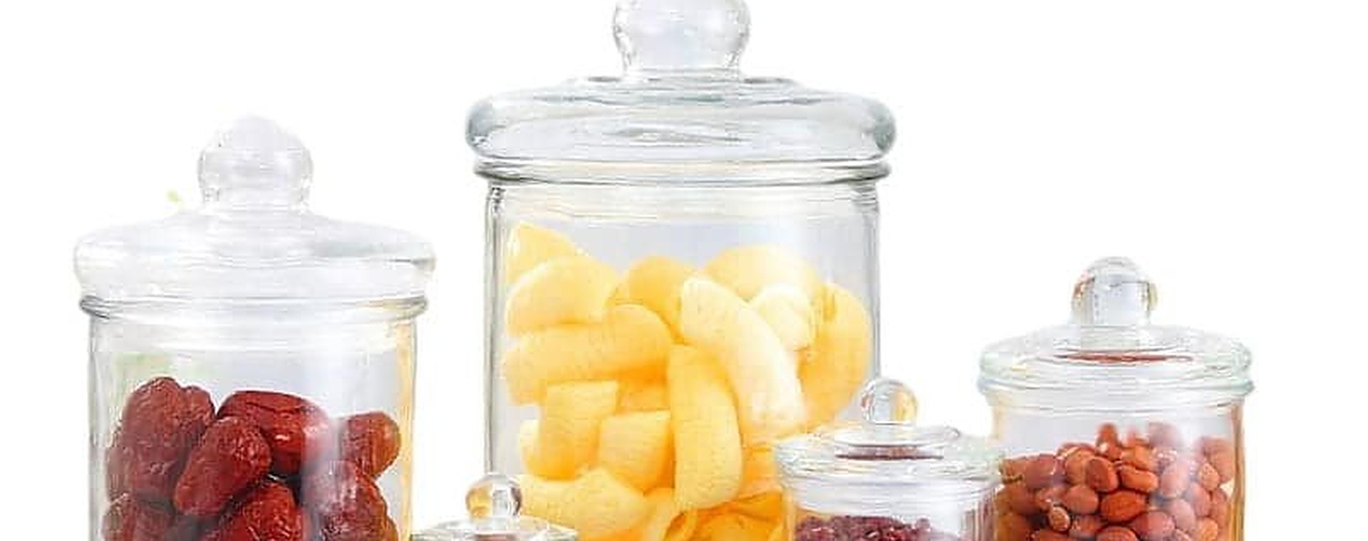 Vier klare Apothekergläser mit Glasdeckeln mit Knauf, gefüllt mit bunten Bonbons