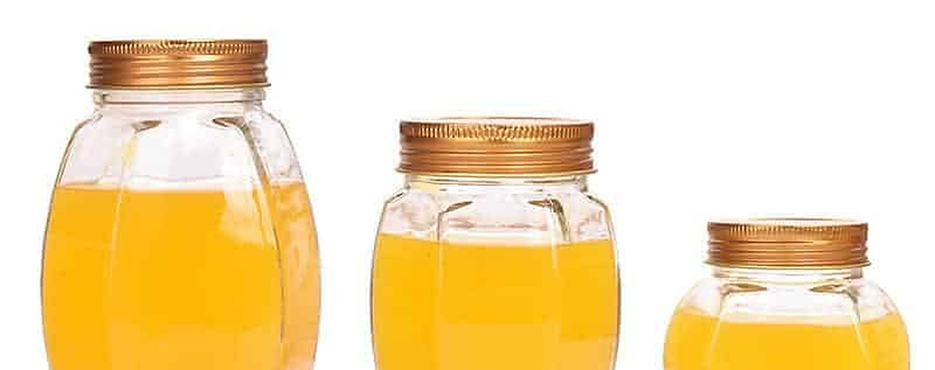 Glass honey jars with paper labels standing on a wooden surface