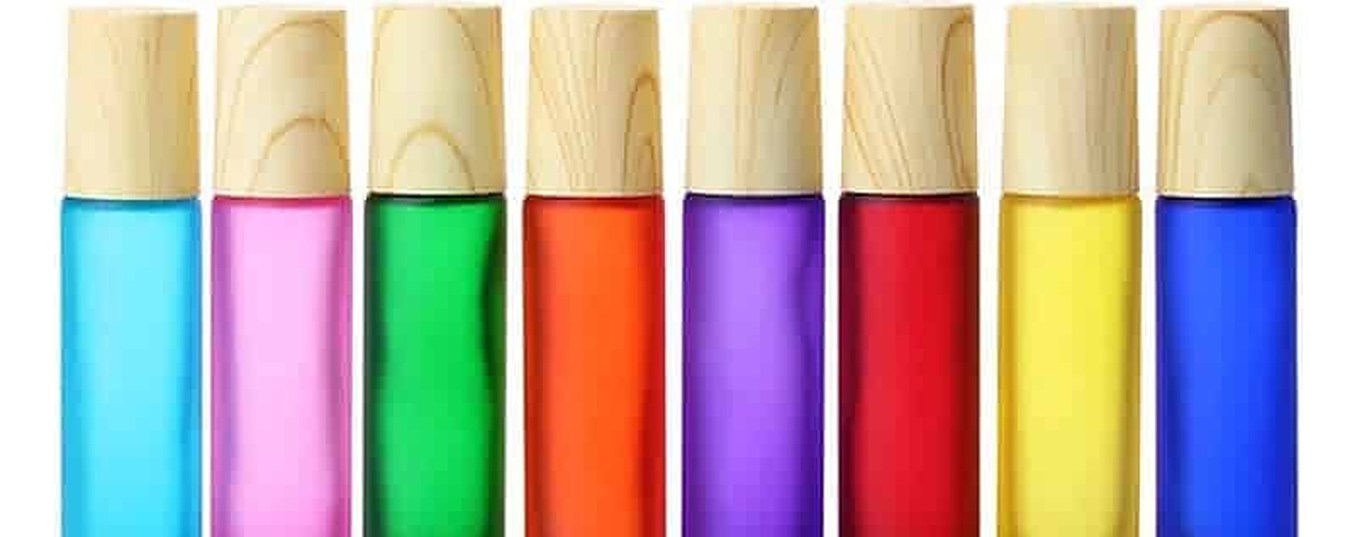 Eight coloured frosted roller bottles with bamboo caps in a row