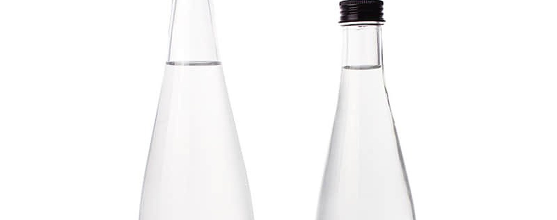 Clear glass water bottles arranged in a row against a plain background