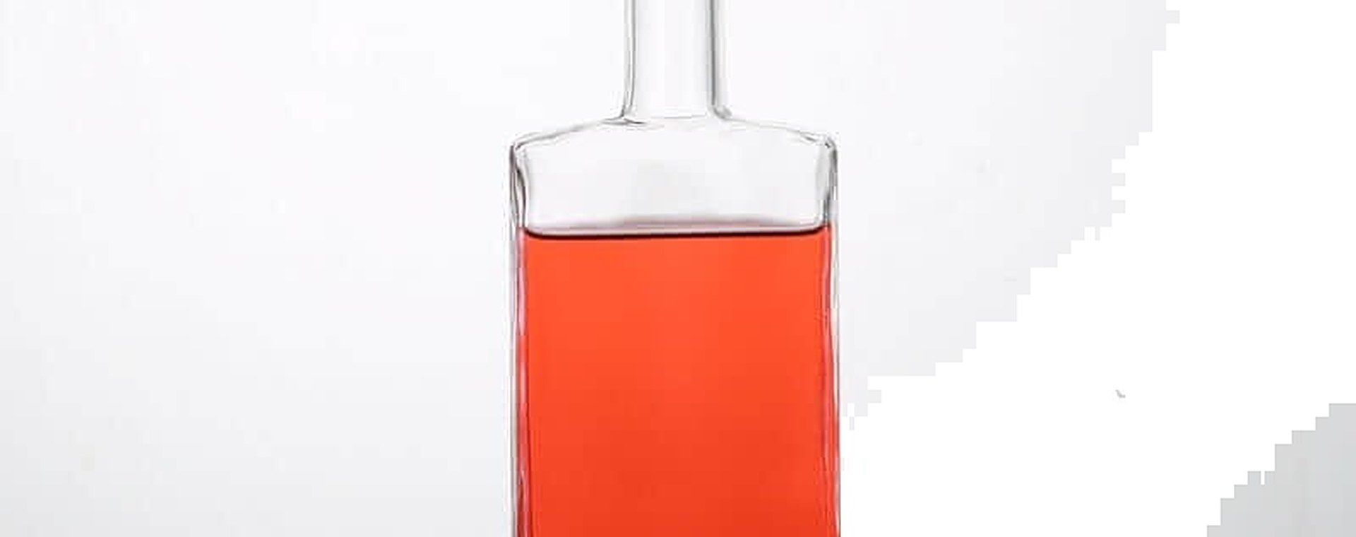 Quadratische Spirituosenflasche mit schwerem Boden aus Klarglas, gefüllt mit einer roséfarbenen Spirituose