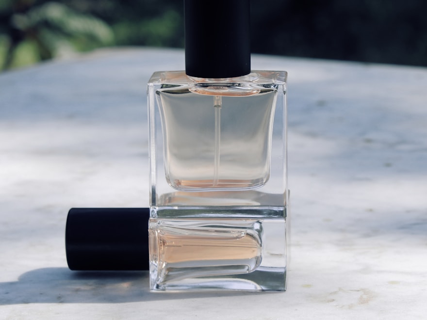 Clear glass perfume bottle with a black crimp cap on marble