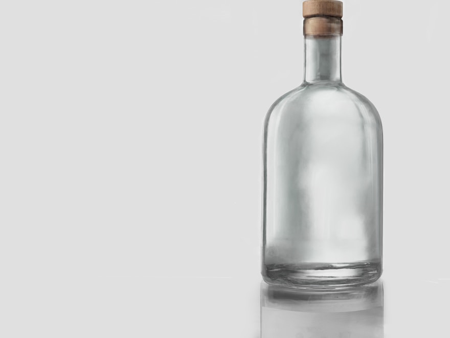 Clear flint glass spirits bottle with a stopper on a grey backdrop