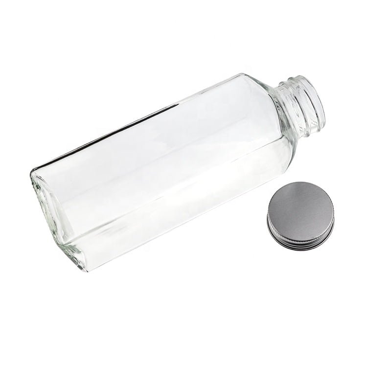 Botellas cuadradas altas de vidrio para leche con tapa plateada, vacías y en fila