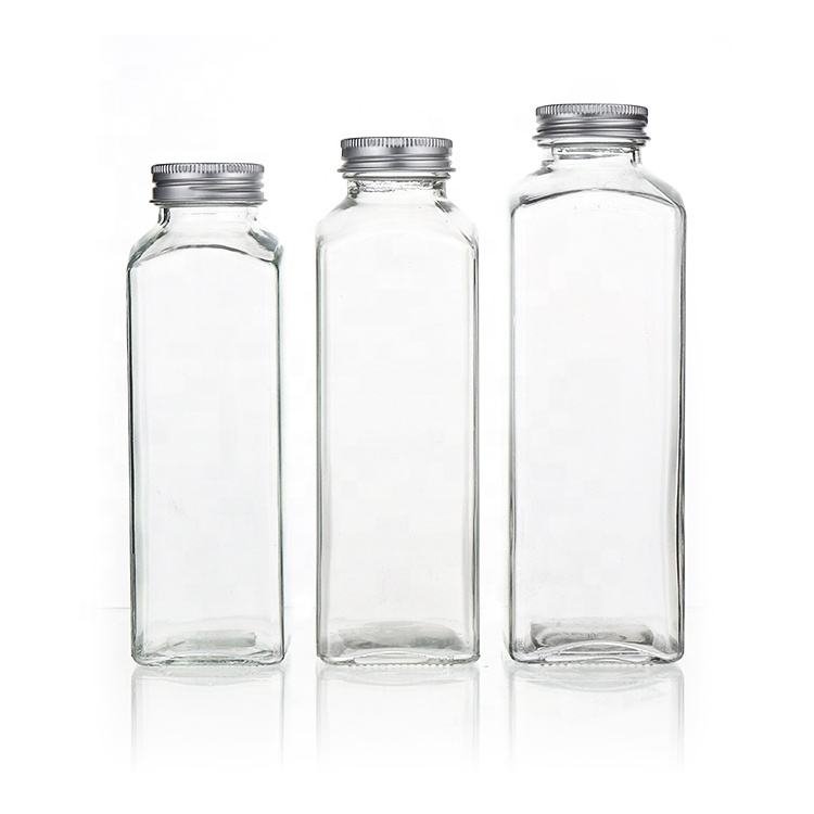 Tres botellas cuadradas altas de vidrio para leche, vacías y con tapa plateada