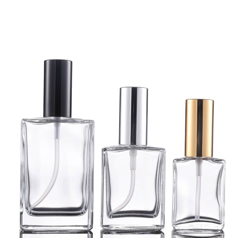 Tres frascos de perfume planos con collarines de atomizador negro, plateado y dorado