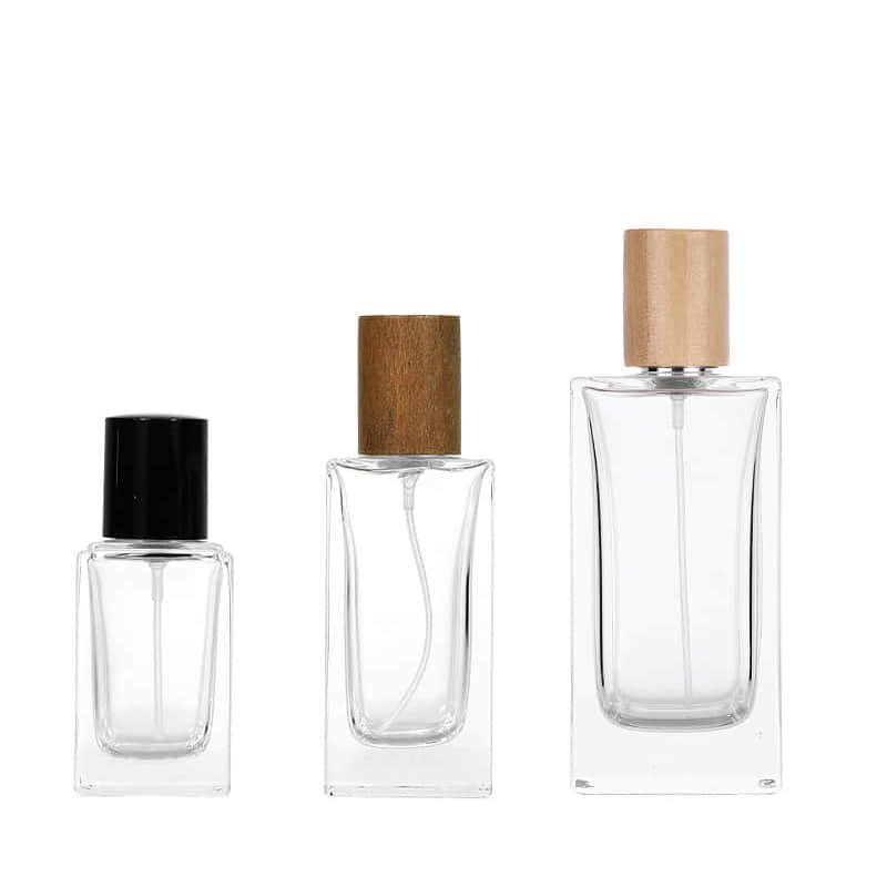 Tres frascos cuadrados de perfume con tapas de atomizador negras y con remate de madera