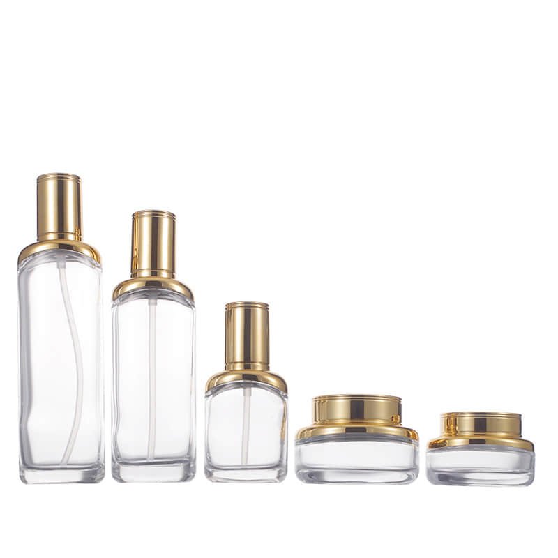 Un set de cosmética con frascos de vidrio con bombas doradas y tarros de crema a juego