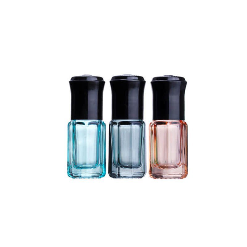 Three faceted tinted glass roller bottles with black caps