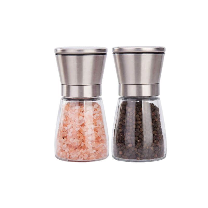 Dos molinillos de vidrio entallados con cabezal de acero inoxidable, llenos de sal en grano y pimienta en grano