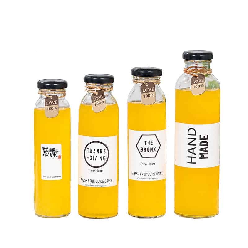 Vier Glasflaschen mit gerader Wand und Papieretiketten, mit Saft gefüllt
