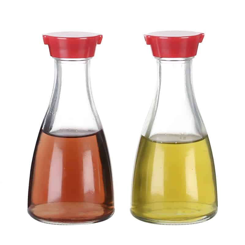 Zwei karaffenförmige Tischflaschen aus Glas mit roten Ausgießerkappen, gefüllt mit Sojasauce und Öl