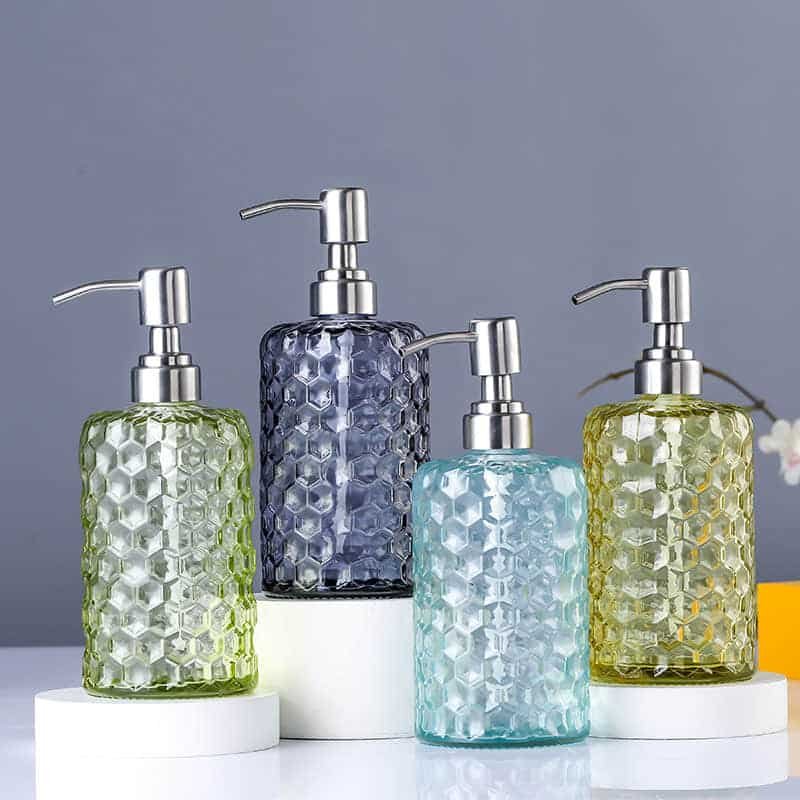 Vier strukturierte Seifenspender aus Glas in Grün, Blau und Grau mit Stahlpumpen