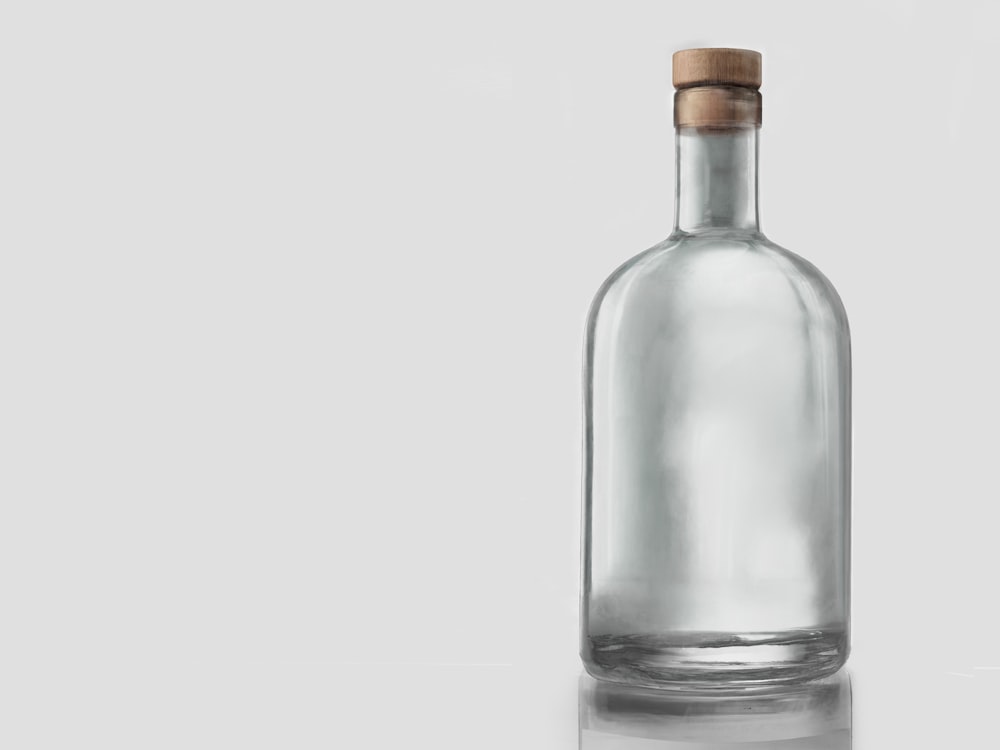 A clear glass sample bottle with a cork stopper on a grey studio background